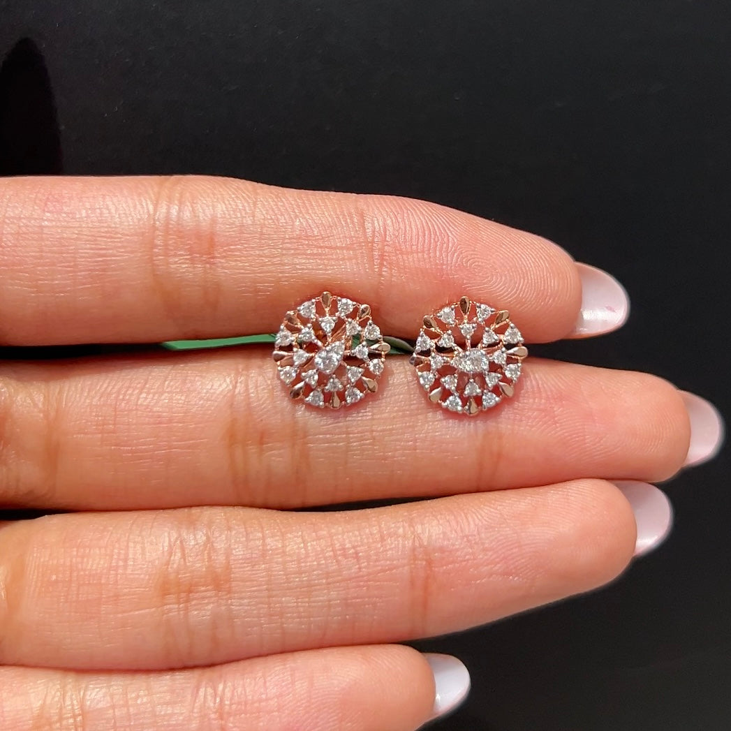 Diamond earrings held between fingers against a black background