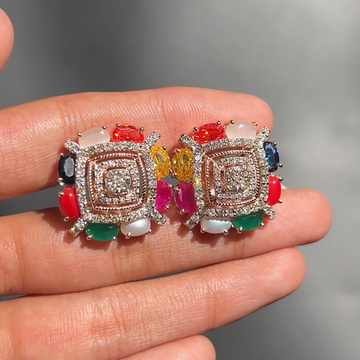 Colorful gemstone earrings held in a hand with a neutral background
